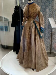 The first outfit we ever displayed was this handmade wedding dress. Worn with pride By Ellen Cummings when she married Thomas Cosway in 1871. The creamy brown fabric with turquoise decoration may seem like an unusual choice for a wedding dress, but white wedding dresses only became popular after Queen Victoria’s wedding in 1840.