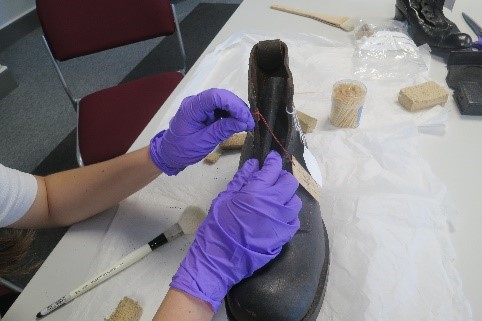 hands wearing gloves cleaning a boot