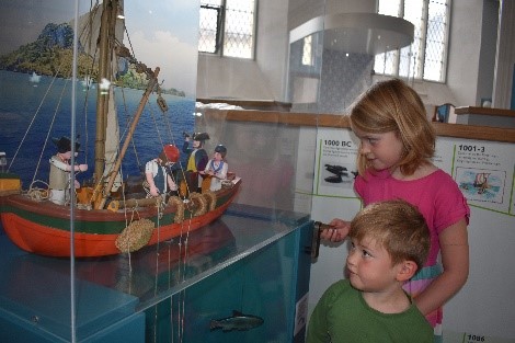 one boy and one girl looking at a painted model of a boat