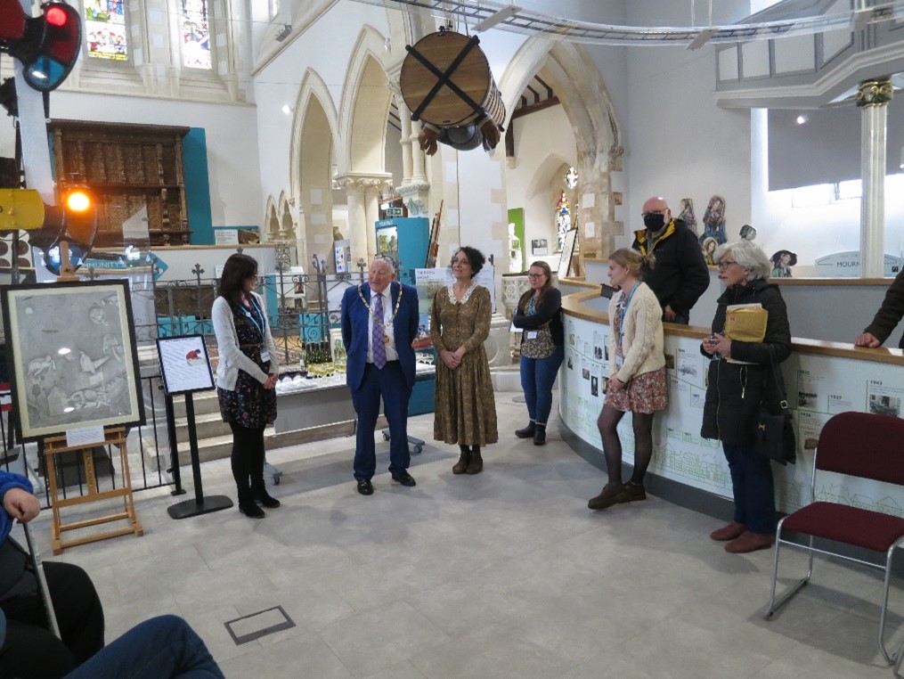 An artist's work being introduced in the museum. Group of people talking with a framed artwork on display