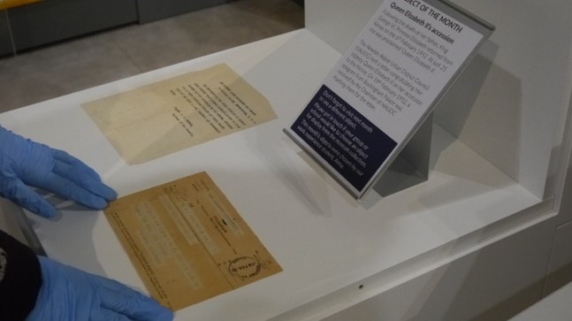 gloved hands placing fragile papers in a display case